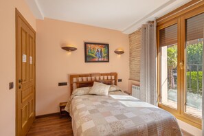 Une chambre à coucher avec un lit en bois, un tableau accroché au mur et une vue par la fenêtre.