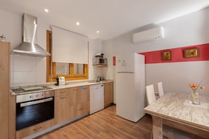 Une cuisine moderne dotée d’un four, d’un micro-ondes et d’un lave-vaisselle encastrés, de meubles en bois et d’un coin repas avec une table et des chaises.