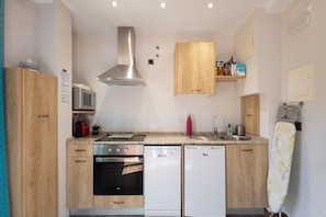 A compact kitchen with a microwave, stove, dishwasher, and wooden cabinets. - Apartment 'Halima' with Balcony, Wi-Fi and Air Conditioning (Daroca)