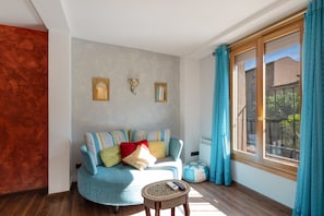 A living room with a sofa, a small round table, a window with curtains, and a radiator. - Apartment 'Halima' with Balcony, Wi-Fi and Air Conditioning (Daroca)