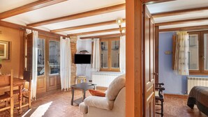 A room with a wooden floor, a sofa, a television, and a window with curtains. - Apartment 'Zayda' with Balcony, Wi-Fi and Air Conditioning (Daroca)