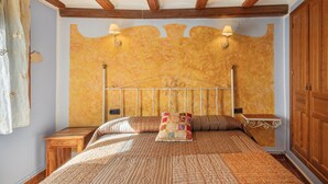 A bedroom with a wooden headboard, two bedside tables, a bed with patterned bedding, and a nightstand with a lamp. - Apartment 'Zayda' with Balcony, Wi-Fi and Air Conditioning (Daroca)