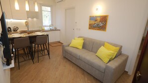 A modern kitchen with white cabinets, a dining table with chairs, and a grey sofa with yellow cushions. - Comfortable apartment in the center of Arenzano, a few steps from the sea (Arenzano)