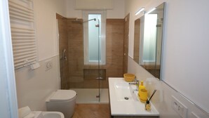 A modern bathroom with a glass-enclosed shower, a white sink with a yellow soap dispenser, and a large mirror. - Comfortable apartment in the center of Arenzano, a few steps from the sea (Arenzano)