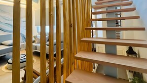 Un interior moderno con un separador de listones de madera, una escalera y vistas al exterior.