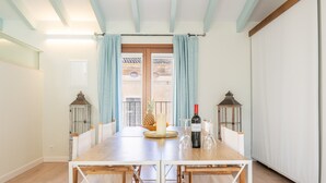 Un comedor con una mesa de madera, sillas, una vela, una botella de vino y dos faroles.
