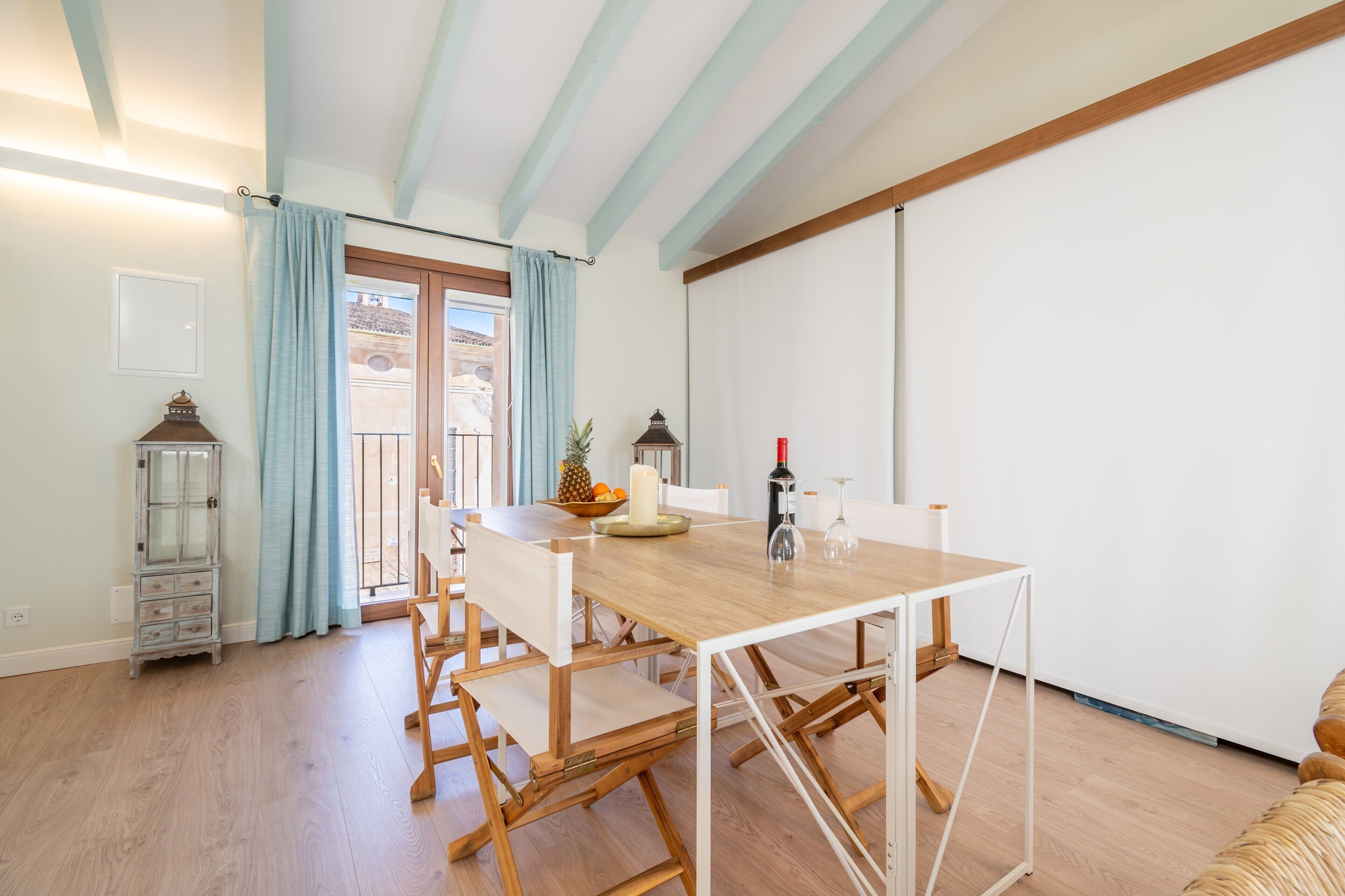 A dining area with a wooden table and chairs, a small cabinet, and a view through a door.