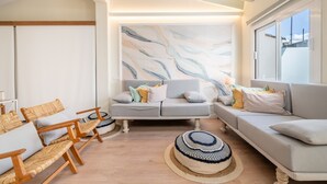 Una sala de estar moderna con un sofá gris, sillas de madera y un cuadro abstracto grande en la pared.
