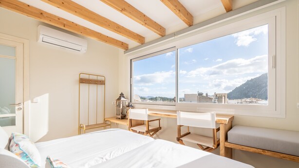 Un dormitorio con un ventanal grande, una cama, un escritorio y una silla.