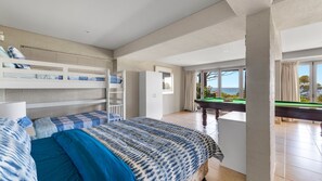Een slaapkamer met stapelbedden, een pooltafel en uitzicht op zee.