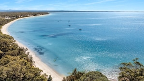 Un paysage côtier avec une plage de sable et des eaux d’un bleu limpide.