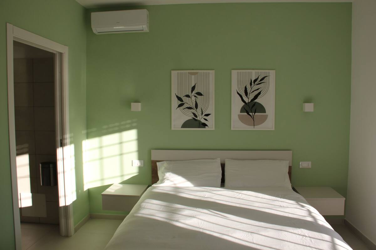 A bedroom with a bed, two nightstands, and two wall-mounted artworks.