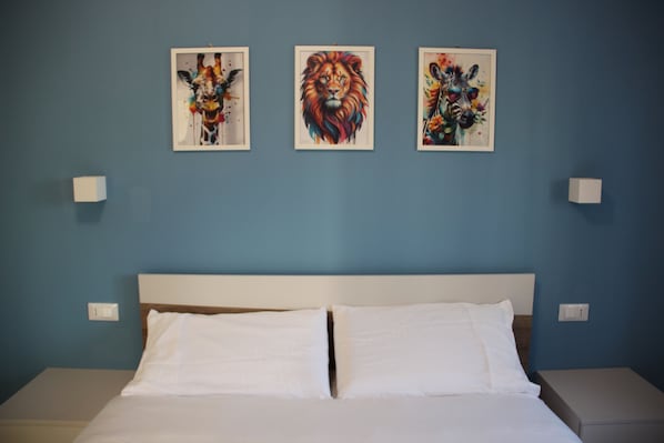 A hotel room with a bed, white pillows, and three framed artworks on the wall. - B&B Il Melograno (Valmontone)