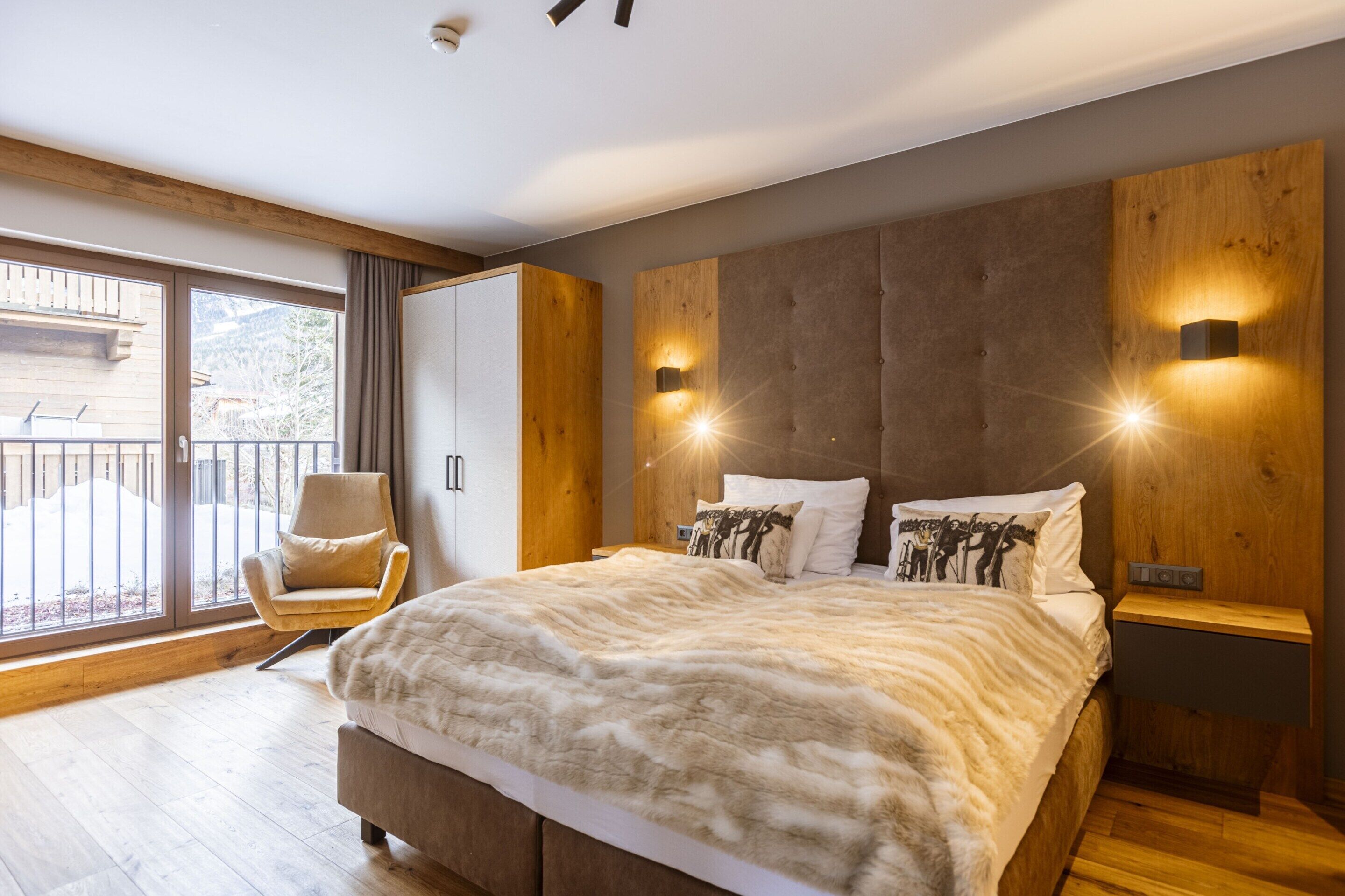 Een moderne slaapkamer met een groot bed, een houten hoofdbord en uitzicht op het landschap door een schuifdeur.
