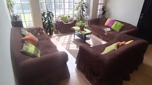 Una sala de estar con sofás marrones, una mesa de centro y plantas en macetas.