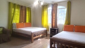 Una habitación con dos camas, una mesita y una ventana con cortinas.
