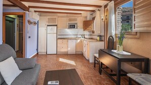 Une cuisine compacte avec des poutres en bois, un coin repas avec une table et des chaises, et un canapé.