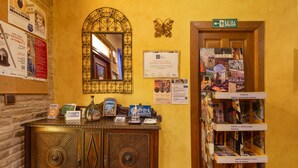Un espace d’accueil comprenant un meuble en bois, un miroir, des éléments de décoration murale et des affiches d’information.