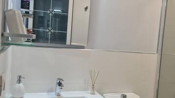 Un baño con lavamanos, espejo y retrete blancos.