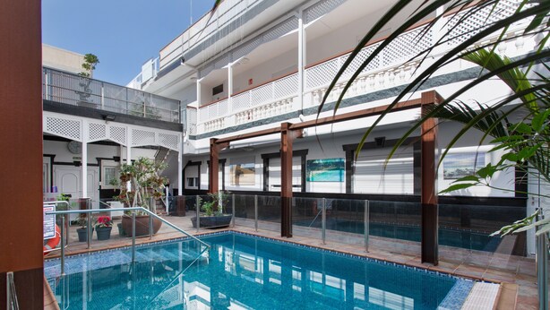 A swimming pool with a glass barrier, a covered area with a balcony, and potted plants. - Vacation Studio 'Paula - 13' with Shared Pool, Shared Terrace and Wi-Fi (Arinaga)