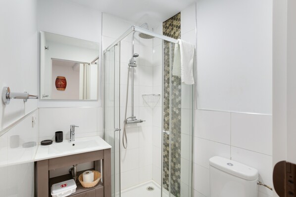 Un bagno moderno con cabina doccia in vetro, lavandino bianco e servizi igienici.