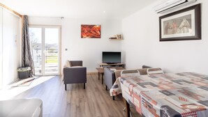 A modern hotel room with a bed, a TV, a sofa, a desk, and a window with curtains. - Family Holiday Home in Lubersac – Pond, Garden, Peace & Comfort (Lubersac)