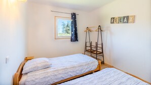 A bedroom with two beds, a window with a view, a hanging light fixture, and a 'RELAX' sign on the wall. - Family Holiday Home in Lubersac – Pond, Garden, Peace & Comfort (Lubersac)