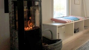 A cozy room with a fireplace, a window with a view, and a bench with pillows. - 6 Person Holiday Home in Venjan (Venjan)