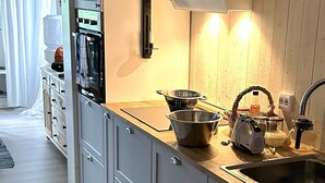 A modern kitchen with grey cabinets, a wooden countertop, a sink, and various kitchen utensils. - 6 Person Holiday Home in Venjan (Venjan)