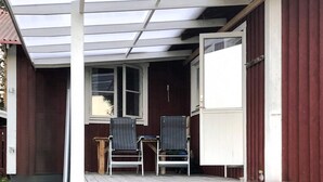 A wooden deck with two chairs and a table, a white door, and a window. - 6 Person Holiday Home in Venjan (Venjan)