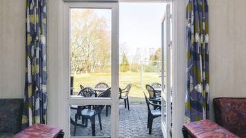 Una habitación con puerta corrediza de vidrio que da a un área exterior con sillas y una mesa.