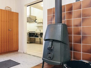 A kitchen with a wood-burning stove, a wooden door, and a tiled backsplash. - 4 Person Holiday Park Home in Laeso (Læsø)