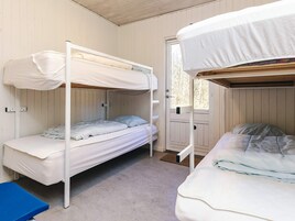 Quarto com duas beliches, um banco azul e uma porta que dá para o exterior.