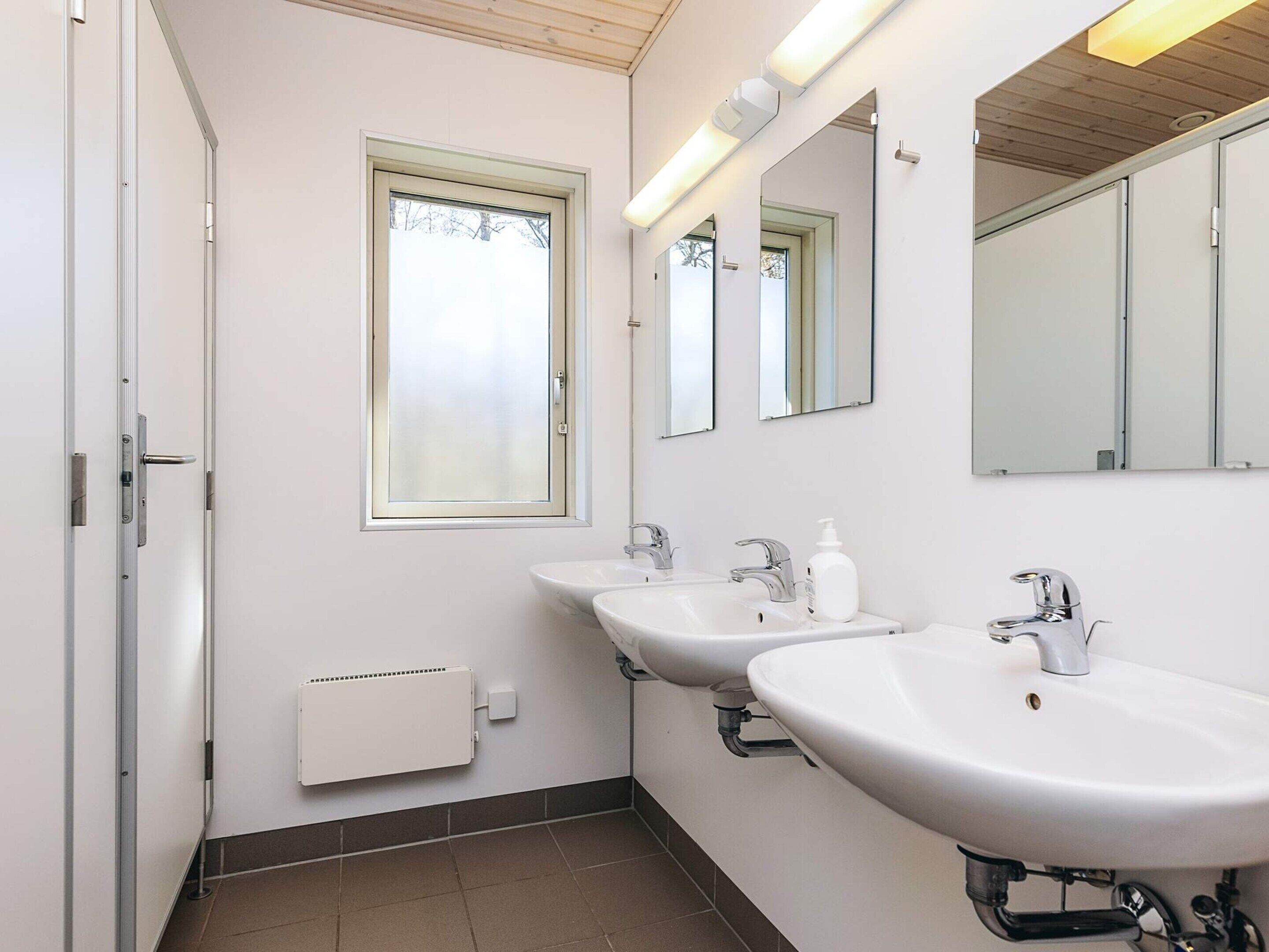 Un baño moderno con dos lavamanos, una ventana y un radiador.