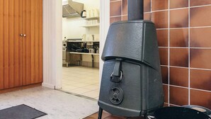 A kitchen with a wood-burning stove, a wooden door, and a tiled backsplash. - 6 Person Holiday Park Home in Laeso (Læsø)