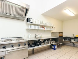 A kitchen with a stove, sink, and shelves with kitchenware.