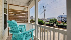 Une véranda couverte avec des fauteuils Adirondack de couleur turquoise et un mur en bois à lattes.