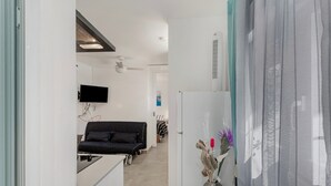 Een modern interieur met een kitchenette, een bank, een flatscreen-tv en een decoratieve vaas.