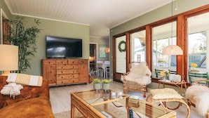 A cozy living room with a television, wooden cabinet, wicker furniture, and a large window. - 6 Person Holiday Home in Vaeggerlose (Vaeggerlose)