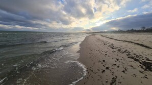 A beach with waves, a sandy shore, and a partly cloudy sky. - 6 Person Holiday Home in Vaeggerlose (Vaeggerlose)