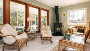 A cozy living room with wicker furniture, a glass coffee table, and a fireplace. - 6 Person Holiday Home in Vaeggerlose (Vaeggerlose)