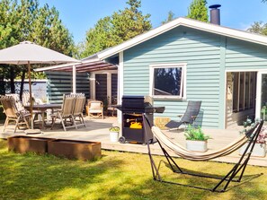 A house with a patio area featuring outdoor furniture, a grill, and a hammock. - 6 Person Holiday Home in Vaeggerlose (Vaeggerlose)