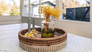 A wicker basket with a glass vase containing yellow flowers on a table near a window. - 6 Person Holiday Home in Vaeggerlose (Vaeggerlose)