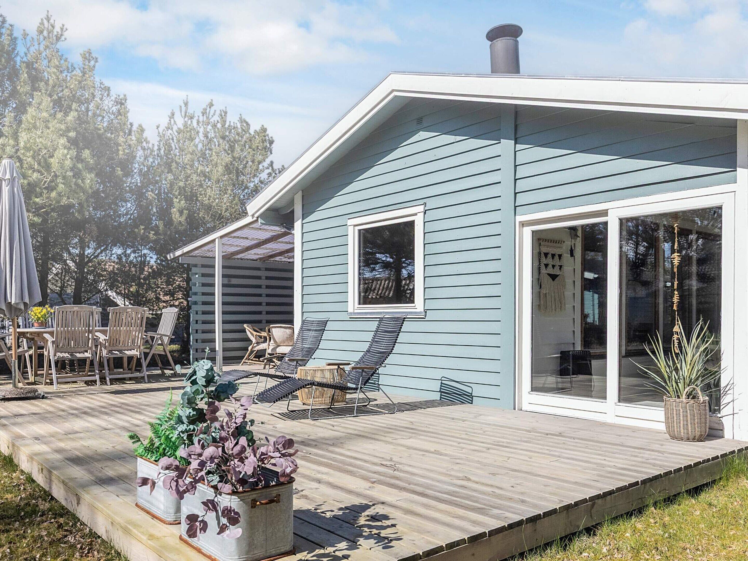 Een modern huis met een terras, tuinmeubilair en een groot raam.