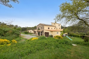 A two-story house with a garden, a slide, and a small shed.