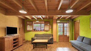 A living room with a wooden ceiling, green walls, a sofa, a television, and a window with curtains. - Rural House 'Cal Panxeta' with Mountain Views, Wi-Fi and Air Conditioning (Balsareny)
