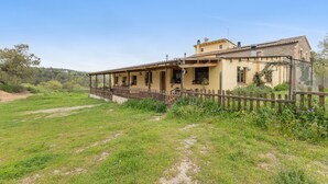 A two-story house with a balcony, surrounded by a fence and greenery. - Rural House 'Cal Panxeta' with Mountain Views, Wi-Fi and Air Conditioning (Balsareny)