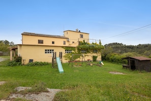 A two-story building with a green slide and a swing set in the yard.
