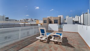 A rooftop terrace with two lounge chairs, a metal fence, and a view of surrounding buildings. - Vacation Studio 'Paula- 23' with Mountain View, Shared Pool and Wi-Fi (Arinaga)