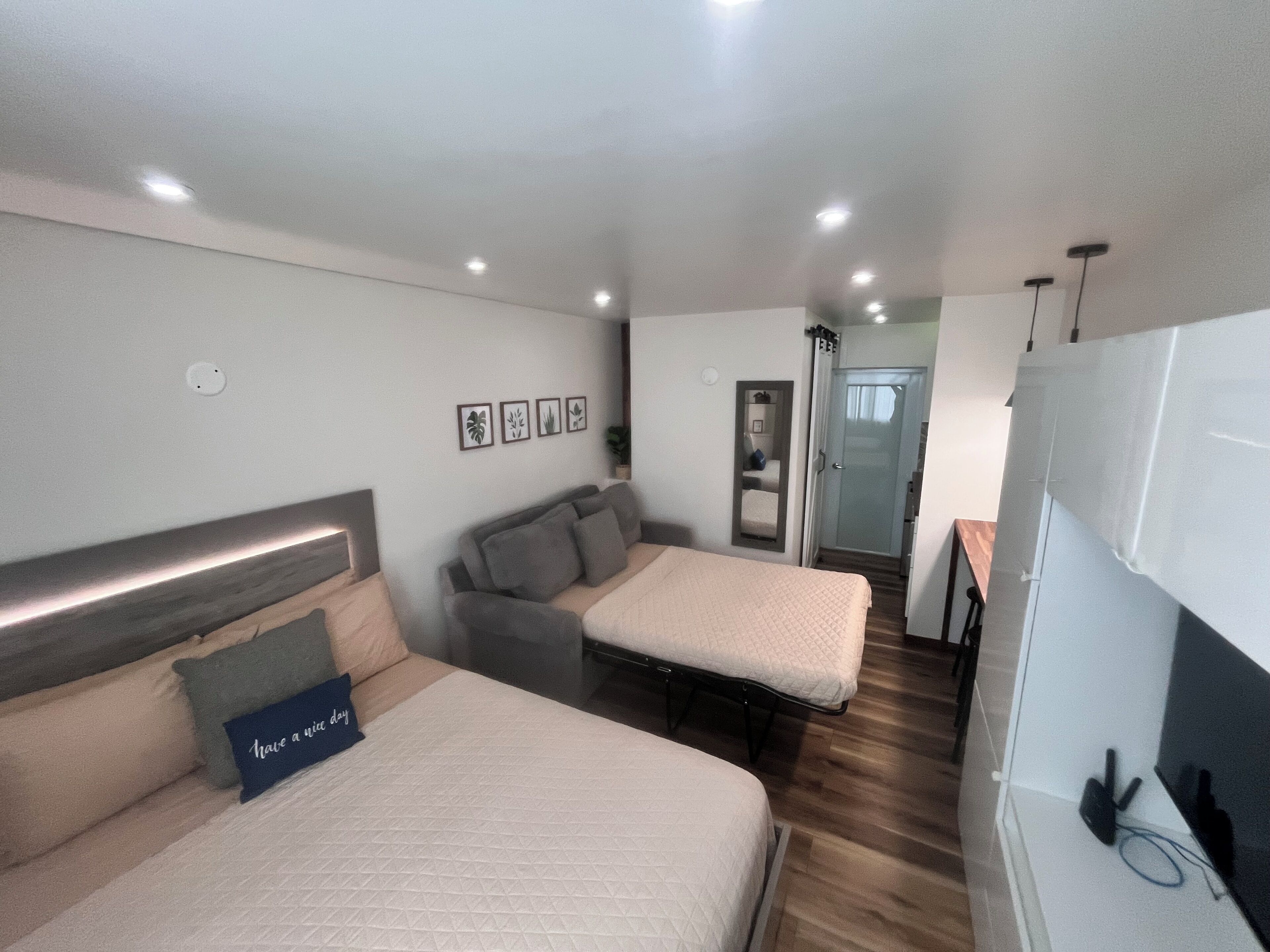 Un dormitorio moderno con dos camas, un sofá, un espejo y un armario.
